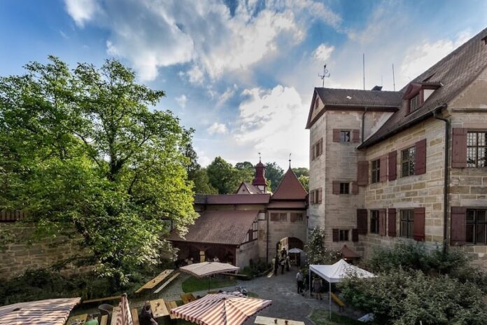Blick vom Wehrgang auf Haupthaus, Treppenturm, Torturm, Glockenturm und Remise. Jedes Jahr am letzten Sonntag der bayerischen Pfingstferien wird der von Wehrmauern umgebene Innenhof zum Schauplatz des Sommerfestes der Stromerstiftung. Foto: Tim Hufnagl Blick vom Wehrgang auf Haupthaus, Treppenturm, Torturm, Glockenturm und Remise. Jedes Jahr am letzten Sonntag der bayerischen Pfingstferien wird der von Wehrmauern umgebene Innenhof zum Schauplatz des Sommerfestes der Stromerstiftung. Foto: Tim Hufnagl